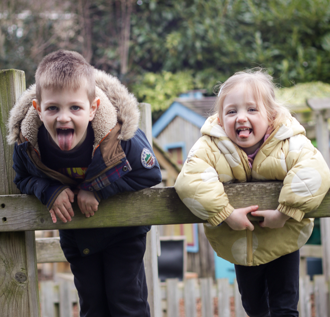 two children on climbing frame sticking their tongues out