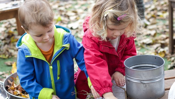 Two children playing with natural materials outdoors